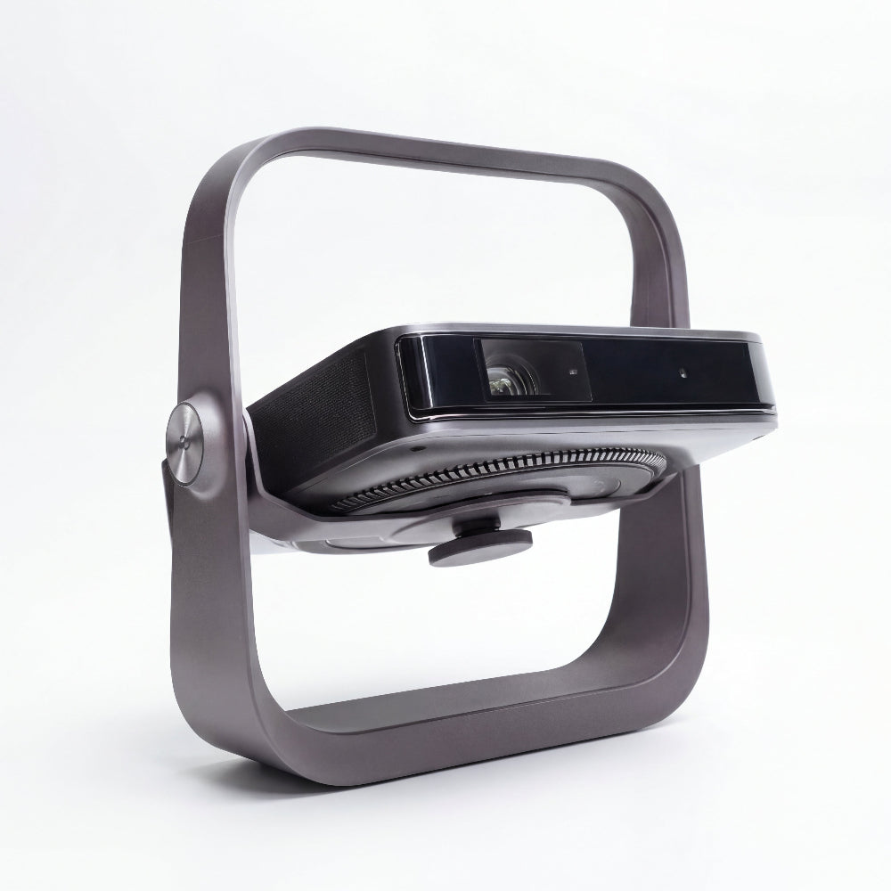 The Dangbei Atom by Dangbei is a modern, rectangular portable projector with a sleek black and silver design, native 1080p resolution, and shown in a metallic open-frame stand against a plain white background.