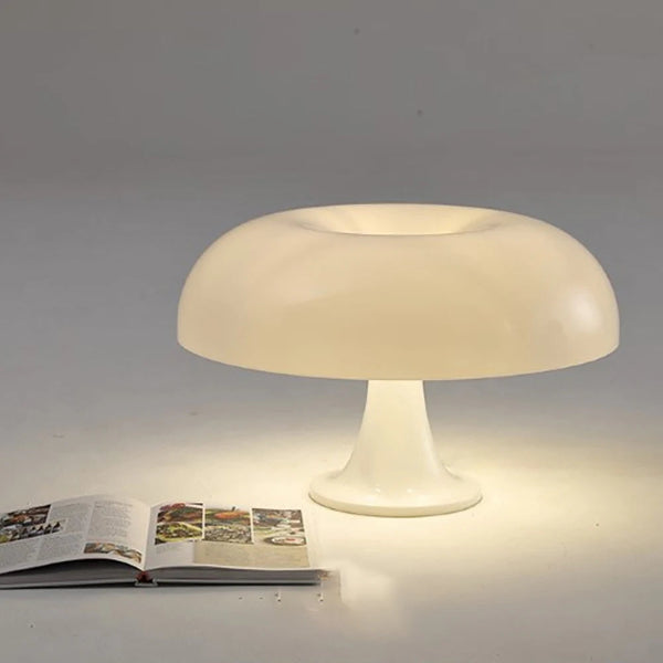 The Projection Room Modern Danish Mushroom Table Lamp features dimmable LED lighting, casting a soft glow over an open book on a light surface.