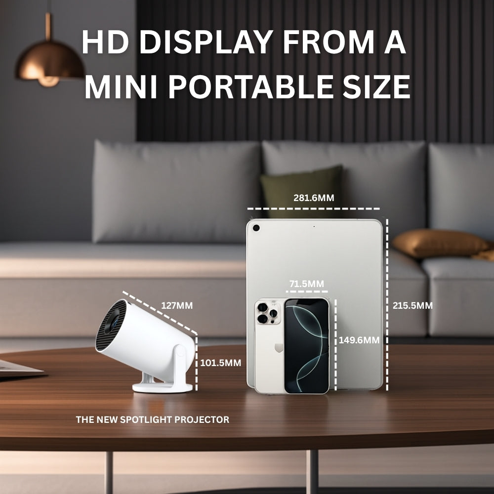 The NEW Spotlight Projector by The Projection Room, a compact white short throw projector, sits next to a smartphone and tablet on a table with measurements in a modern living room. Text above reads: "HD DISPLAY FROM A MINI PORTABLE SIZE.