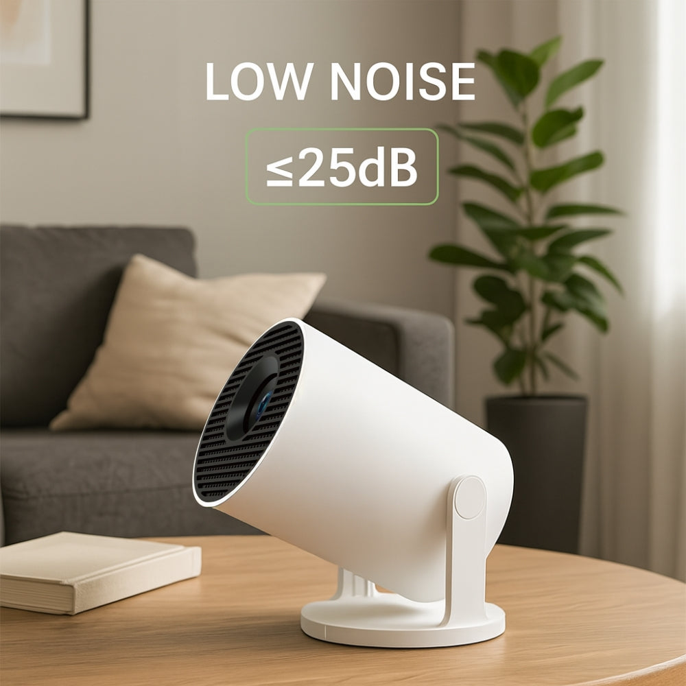 The NEW Spotlight Projector by The Projection Room—a white, cylindrical short throw projector—rests on a wooden table in a modern living room. Text above reads “LOW NOISE ≤25dB.” A sofa, plant, and picture frames complete the scene.