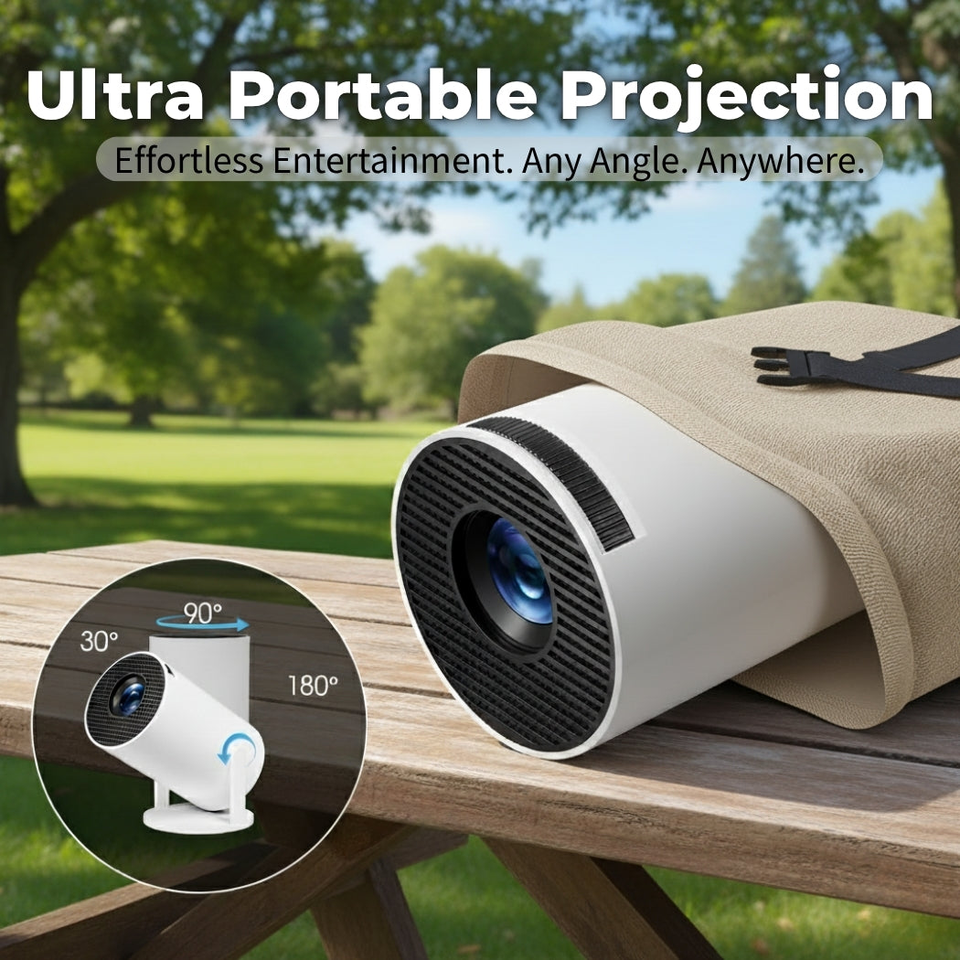 The Spotlight Projector by The Projection Room, a compact white portable projector, rests on a wooden outdoor table with trees and grass in the background. Text: "Ultra Portable Projection. Effortless Entertainment. Any Angle. Anywhere.