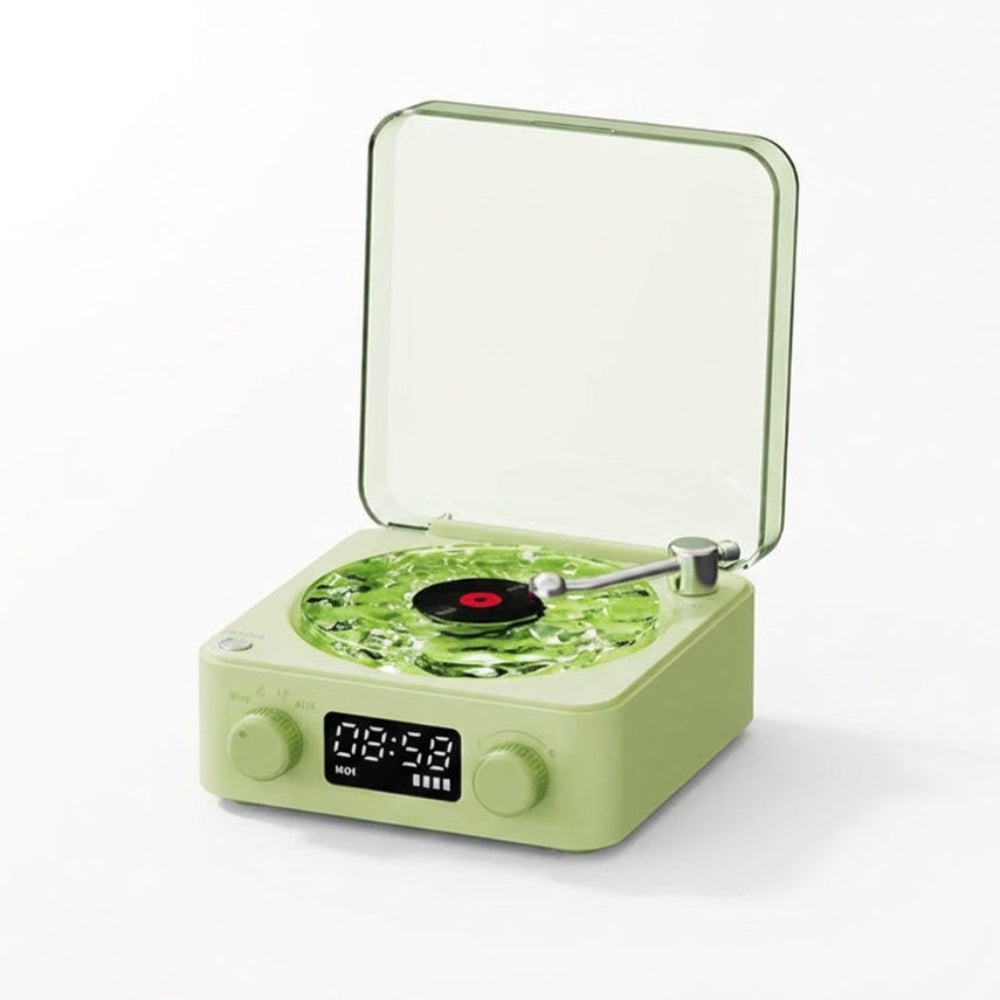 The Projection Room Vinyl Speaker Lamp is a small, light green retro-style device with Bluetooth streaming, digital clock display, knobs, and a clear hinged lid. The turntable holds a miniature black vinyl record.