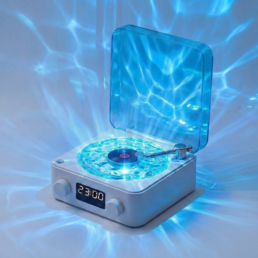 The Projection Room’s Vinyl Speaker Lamp features a retro design with a transparent blue lid, glowing blue lights that project water-like reflections, Bluetooth streaming, two control knobs, and a display showing 23:00 for high-quality audio.