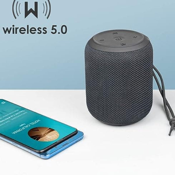 Wireless portable Speaker placed on top of a table next to a phone