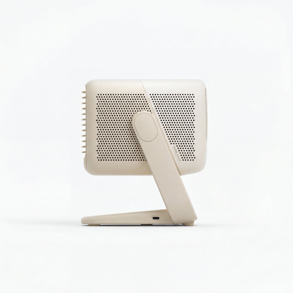 A side view of the beige JMGO N1S Nano by JMGO shows its perforated panel and adjustable stand, featuring Google TV and resembling a compact tabletop fan or air purifier.