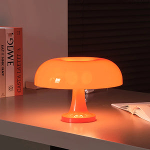 The Projection Rooms Modern Danish Mushroom Table Lamp LED Bedside Lamp glows warmly on a desk, surrounded by neatly stacked books and an open notebook in a softly lit room.