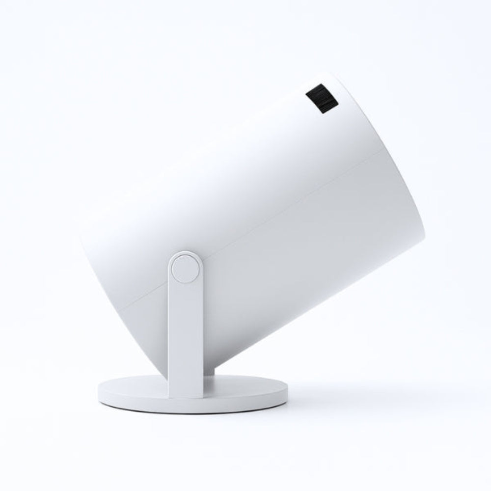 The Spotlight Projector by The Projection Room is a modern cylindrical white projector on a circular base, angled upward, featuring HD quality and wireless streaming, set against a plain white background.