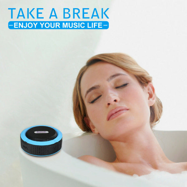 A woman relaxes in a bathtub, eyes closed, with The Projection Rooms Portable Waterproof Wireless Mini Bluetooth Music Speaker (featuring a blue rim) near the edge. Text: TAKE A BREAK -ENJOY YOUR MUSIC LIFE WITH HIGH-FIDELITY SOUND-.